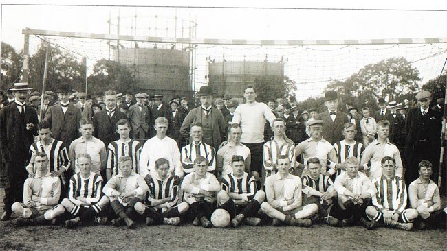IK Start in Danmark 1912. The picture shows Danish AaB (striped kits) and Start (blue and white squares).. Starts team is in front from left: Gustav Eriksen, Arne Johnsen, Albert Egeland, Bernhard Knudsen, Trygve Berthelsen and Max Horrisland. Behind from left: Johan Jahnsen, Einar Kristiansen, Thomas Svendsen, Arthur Aune Iversen, Ole Tobias Thorstensen and Otto Hulthin (in a suit and a six-pence hat). Start was missing two of its best players - Reinholdt Samuelsen and Einar Torjesen - and lost clearly 1-4 against the Aalborg club on Danish soil.